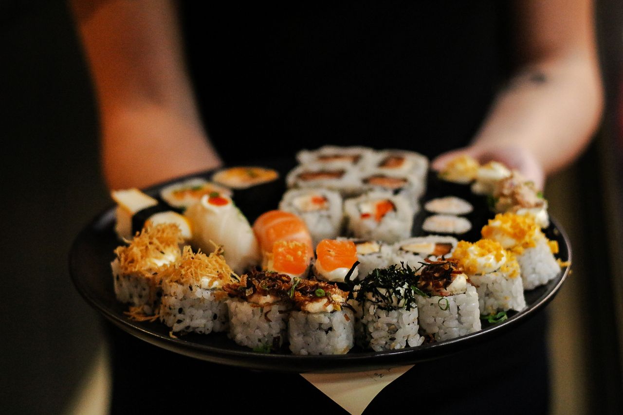 Home Close-up of a variety of delicious sushi rolls on a black plate, showcasing vibrant ingredients.
