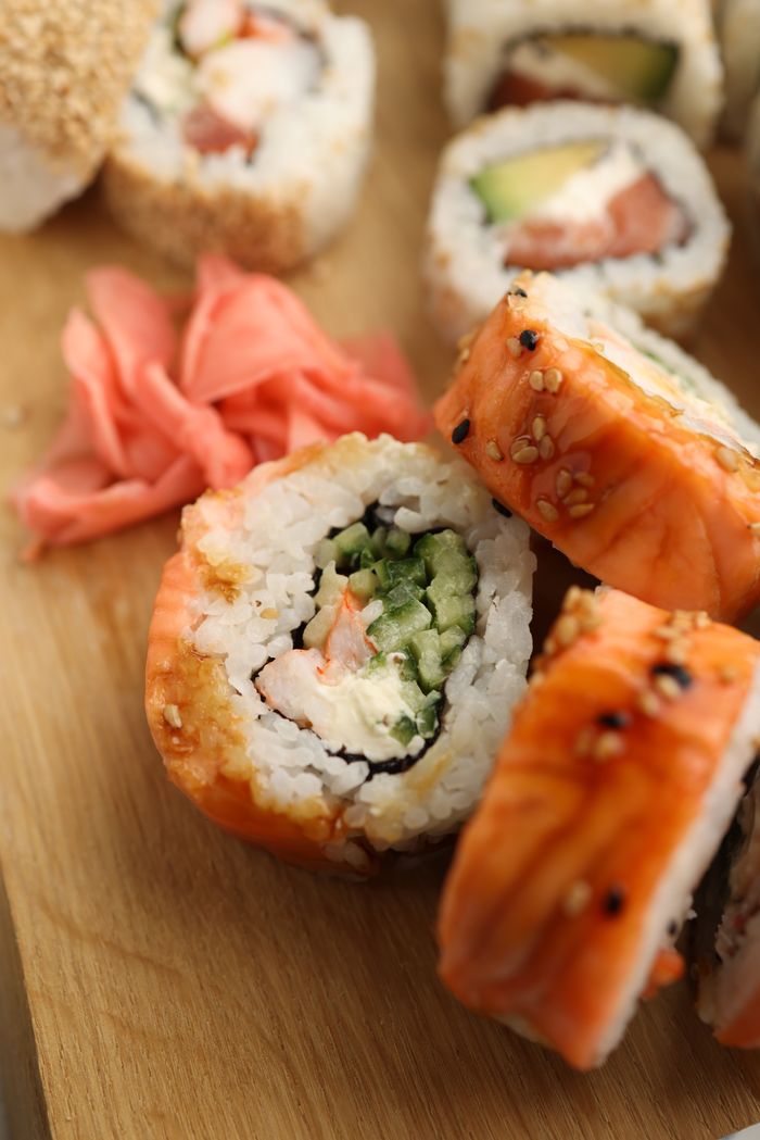 Home Close-up of delicious sushi rolls with rice, seafood, and sesame seeds on a wooden board.