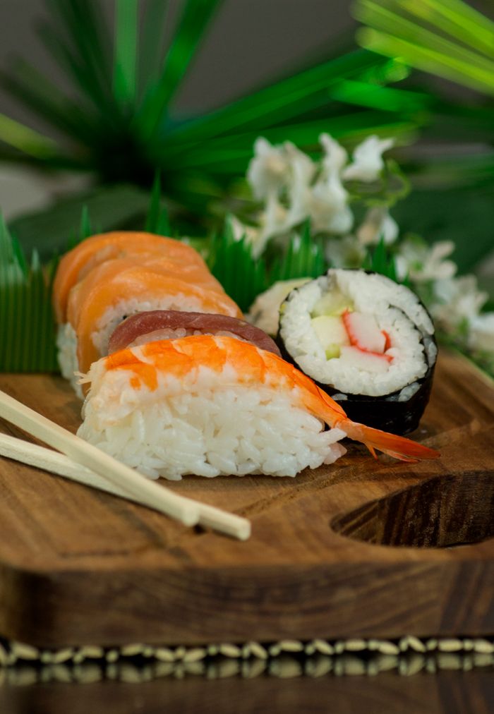 Japanese sushi assortment on a wooden tray, featuring rice, seafood, and chopsticks. Perfect for food photography.