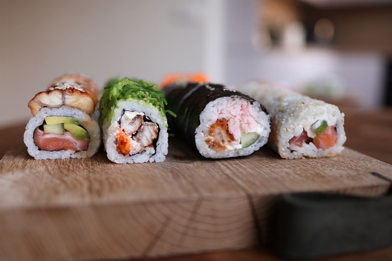 Home Close-up of assorted sushi rolls on a wooden board showcasing fresh ingredients.