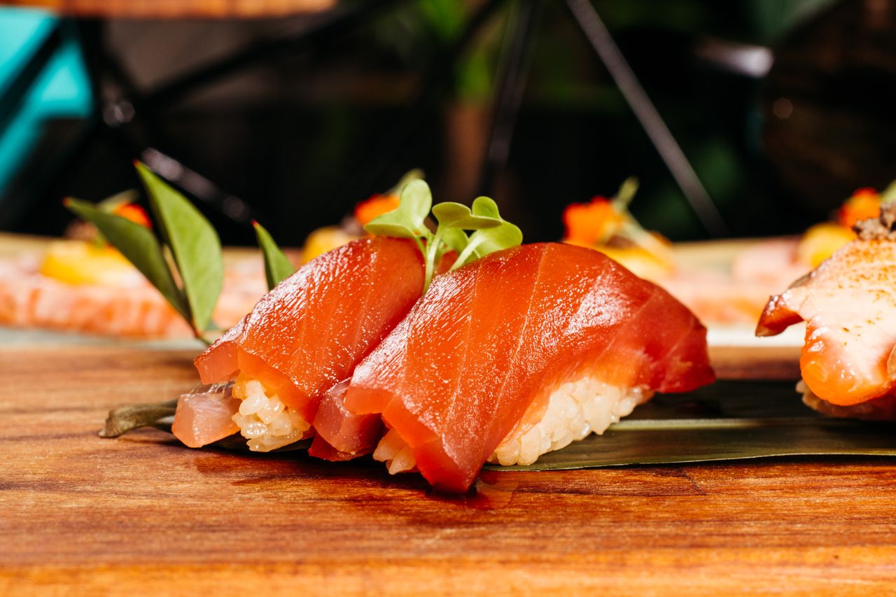 Home Delicious slices of salmon nigiri sushi served beautifully on a wooden platter with garnish.